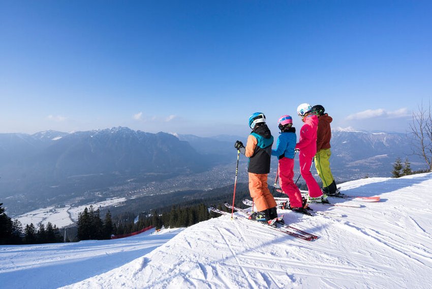 четверо лыжников стоят на вершине в горах